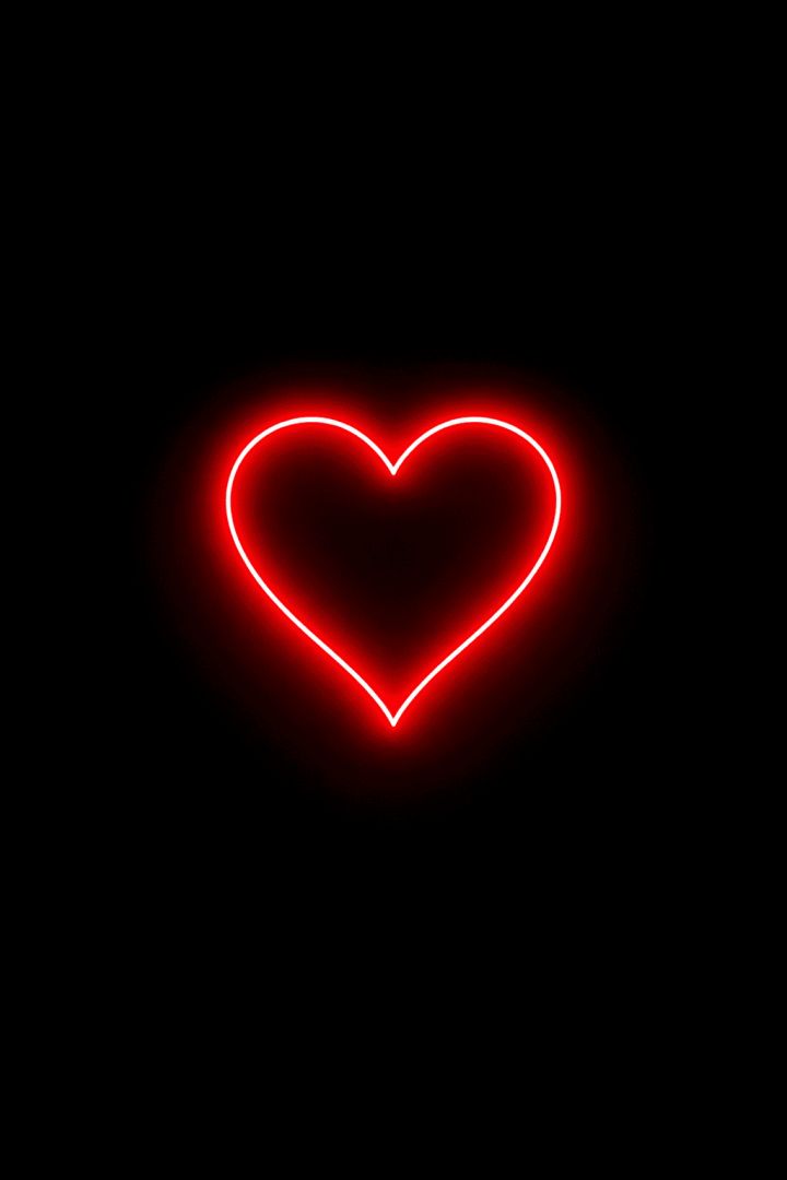 Glowing neon heart on black background wallpaper