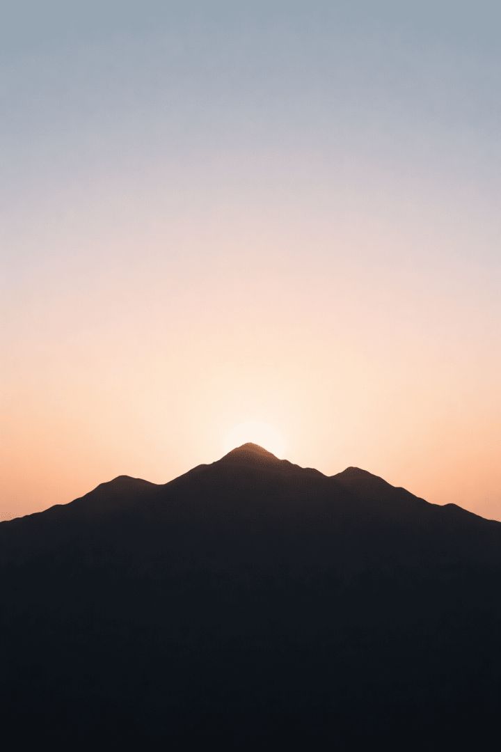 Serene mountain sunrise with soft glow minimalist wallpaper